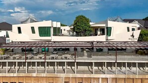 A modern hotel with a rooftop terrace, multiple balconies, and a prominent logo. - The Rachata Ayothaya (Ayutthaya)