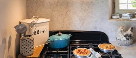 Een keuken met een zwarte kookplaat, een blauwe pan en een broodtrommel.