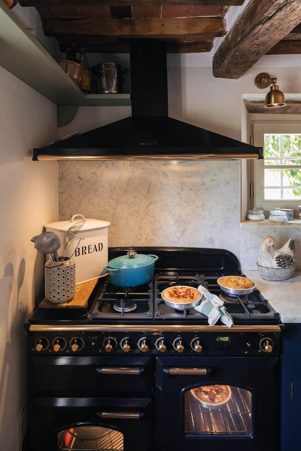Une cuisine avec un poêle noir, une casserole bleue et un récipient à pain.