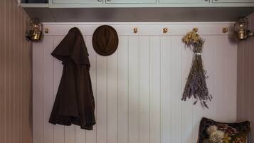 A wooden bench with storage shelves underneath, a hanging coat, and a wall-mounted hat rack.