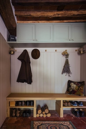 Un banc en bois doté d’étagères de rangement en dessous, un manteau suspendu et un porte-chapeaux fixé au mur.