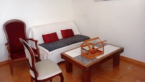 A room with a red chair, a white sofa with red cushions, a small wooden table, and two paintings on the walls. - Dorm 2 between Trega and Minho A GUARDA (A Guarda)