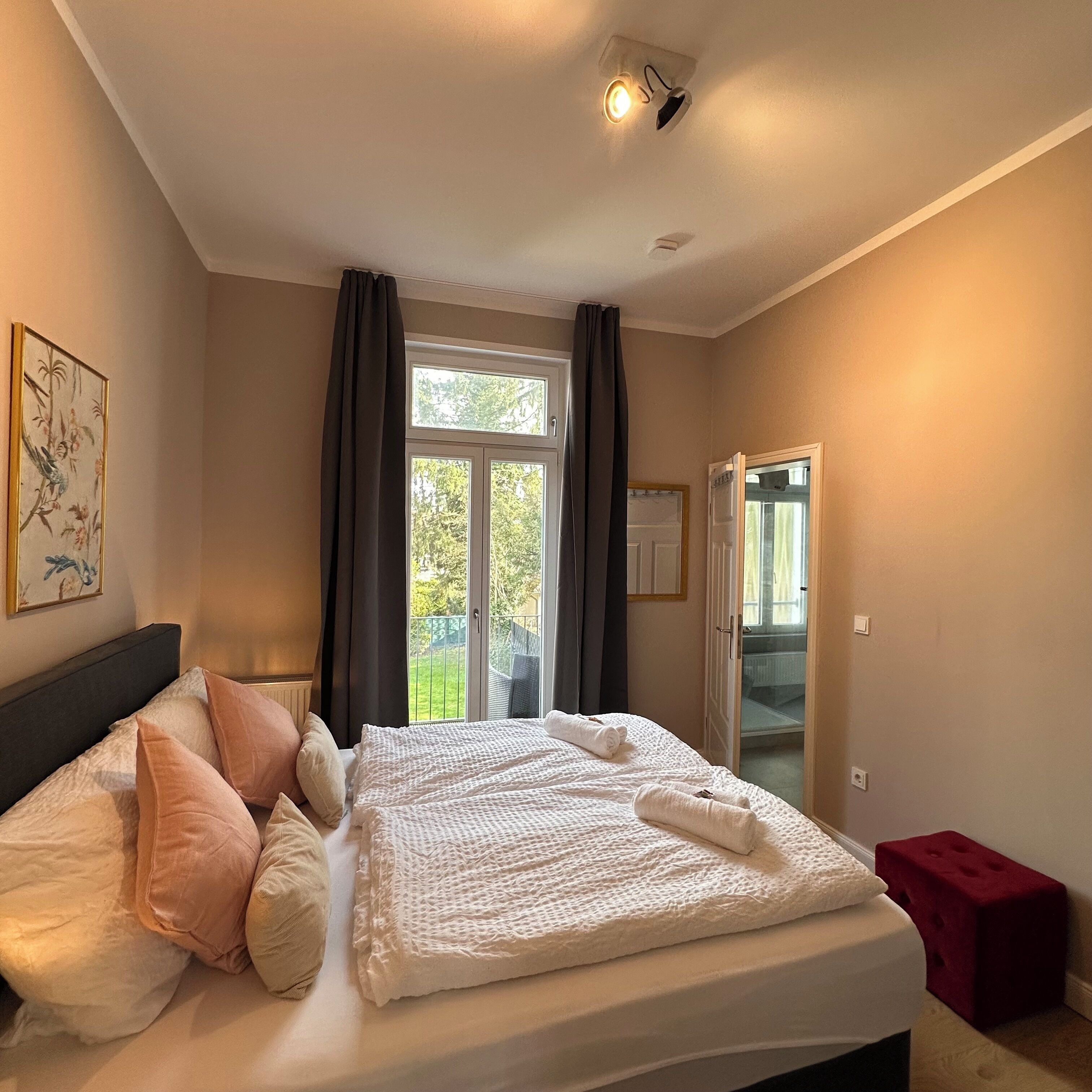 Ein Schlafzimmer mit einem Bett, einem Fenster, einer Tür und einem Bild an der Wand.