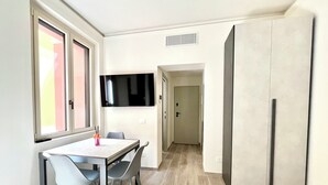 A modern kitchen with a dining area, a TV mounted on the wall, and a refrigerator. - Garibaldi Living - Centro Storico Parma (Parma)