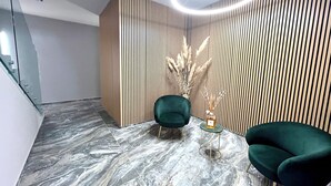 A modern interior with a marble floor, a green armchair, a small round table, and a vertical wooden panel wall. - Garibaldi Living - Centro Storico Parma (Parma)