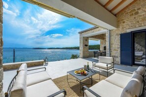A terrace with outdoor seating, a table with food, and a view of the sea. - Villa Proversa (Ždrelac)