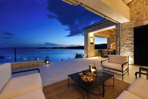 A terrace with a view of the sea, stone walls, and outdoor seating. - Villa Proversa (Ždrelac)