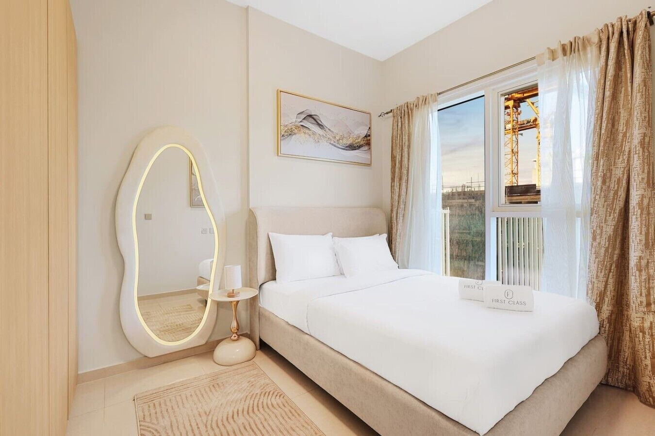 Quarto de hotel com cama, espelho, pintura e vista para uma ponte.