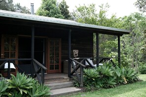 Eine Holzlaube mit Veranda, Treppe und einer Tür.