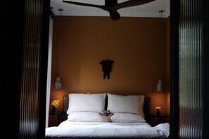 Ein Schlafzimmer mit einem Bett, einem Deckenventilator und einer Wandleuchte.