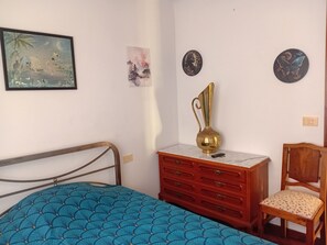 Quarto com cama, penteadeira, cadeira e quadros na parede.