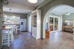Eine geräumige Küche mit weißen Schränken, ein Essbereich mit Tisch und Stühlen sowie eine große Glasschiebetür, die zu einer Außenpatio führt.