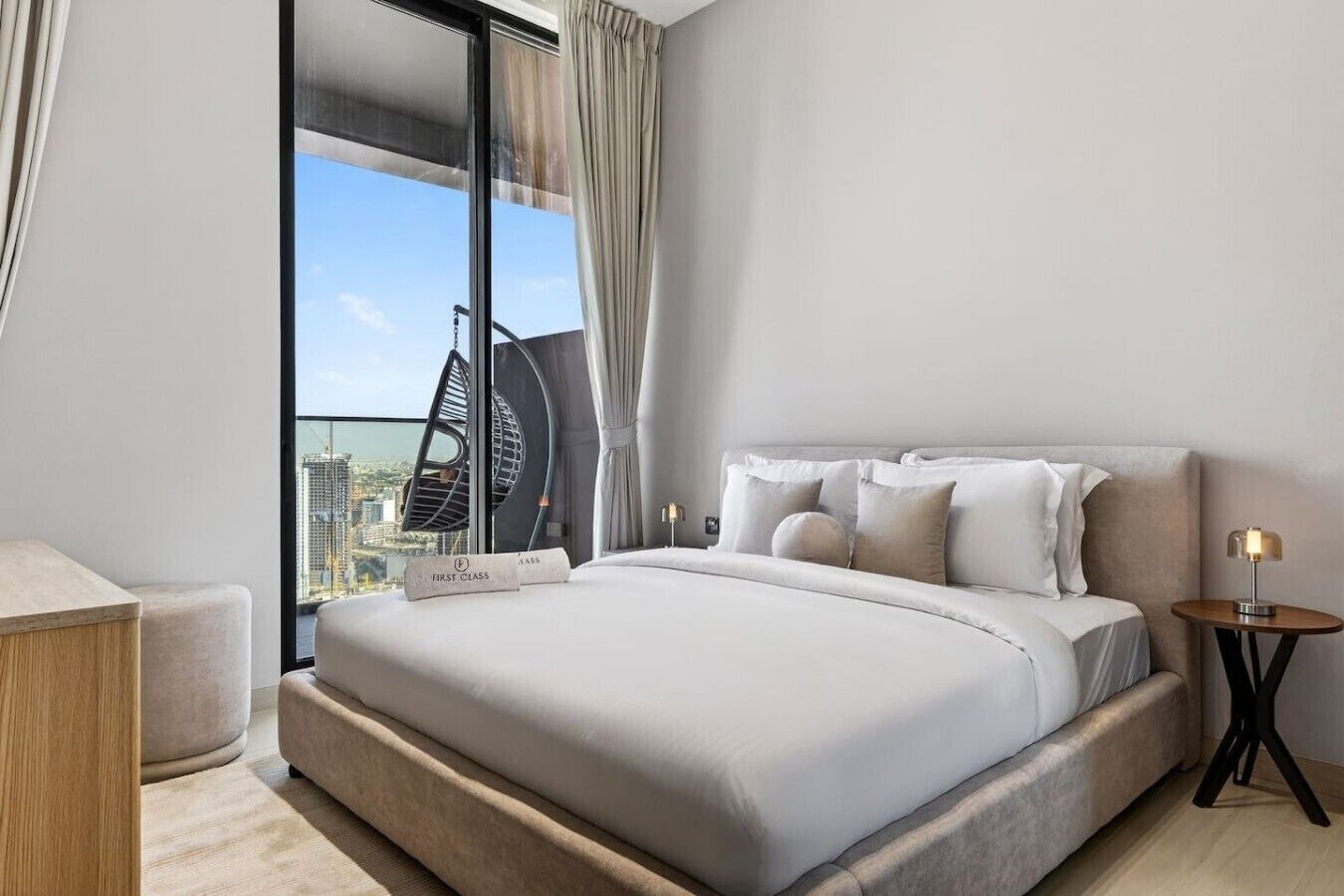 Moderni hotellihuone, jossa on suuri sänky, näköala kaupungin ylle ja parveke, jossa on riipputuoli.