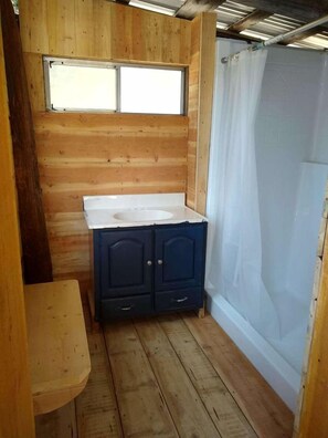 A small, wooden cabin-style bathroom with a window, a sink, and a shower curtain. - Sanctuary Yurt Glamping Forest Getaway in Alberton, MT (Alberton)