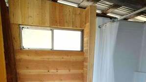 Une petite salle de bain de style cabane en bois, avec une fenêtre, un lavabo et un rideau de douche.