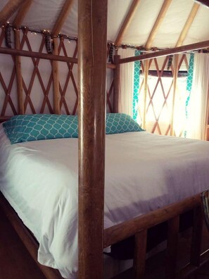 A single bed with a wooden frame and white bedding, a wooden ceiling, and a window with curtains. - Sanctuary Yurt Glamping Forest Getaway in Alberton, MT (Alberton)