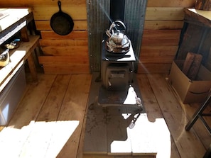 A compact kitchen with a stove, a kettle, and a pan on the wall.