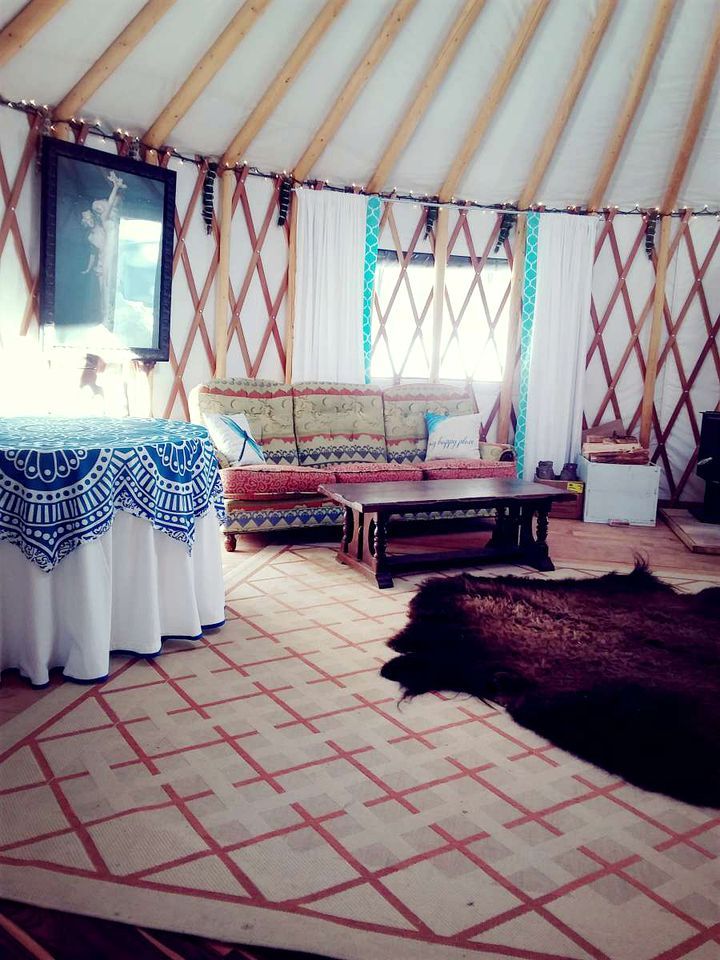 A yurt interior with a sofa, a table, and a rug.