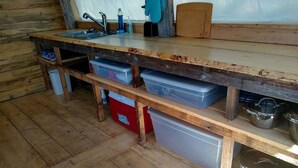 Une cuisine rustique avec des étagères en bois, un évier et des récipients de rangement.