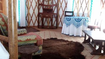 Interior de una yurta con una silla de madera, una mesa y una alfombra.