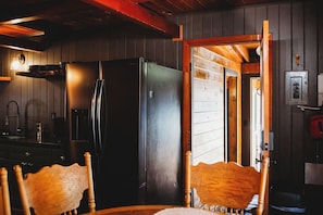 A kitchen with a black refrigerator, wooden chairs, and a wooden table. - Bigfoot Alley | Movie Room + Walkable Location (Shaver Lake)