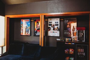 Een kamer met een donkerblauwe bank, een muur met filmposters en een automaat met snacks.
