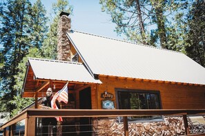 A wooden cabin with a stone chimney, a balcony, and a sign that reads 'The Chate'. - Bigfoot Alley | Movie Room + Walkable Location (Shaver Lake)