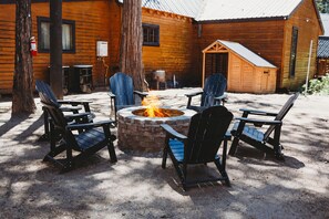 A wooden cabin with a fire pit and Adirondack chairs arranged around it. - Bigfoot Alley | Movie Room + Walkable Location (Shaver Lake)