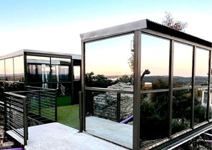 Eine moderne Glasarchitektur mit Metallgeländer, einer Steinsäule und Blick auf die Landschaft.