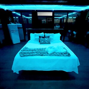 A room with a bed, a small refrigerator, and a window.