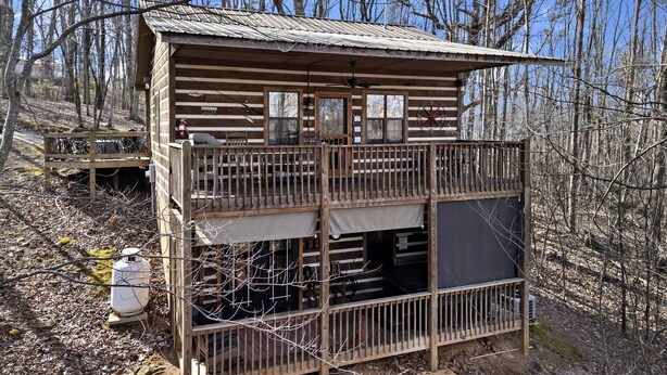 A rustic cabin with a balcony, a fire extinguisher, and a water tank. - Peaceful Mountain Cabin with Mt Yonah Views with Fire Pit and Outdoor Dining in Sautee Nacoochee, Georgia (Sautee Nacoochee)