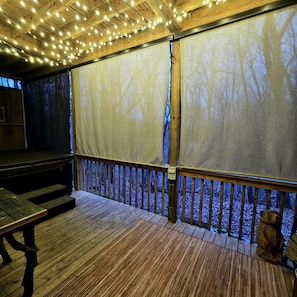 Eine Holzterrasse mit Geländer, einer Bank und einer Bärenstatue.