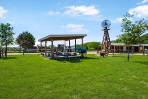 Ein Picknickplatz mit Tischen, Stühlen, einer Windmühle und einem Schutzhaus.