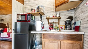 A compact kitchen with a refrigerator, microwave, and wooden cabinets. - Charming Riverside Cabin Escape with Outdoor Relaxation Spaces in Medina, Texas (Medina)