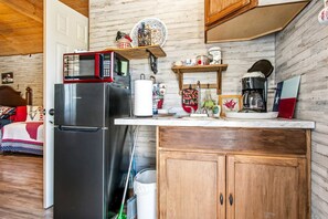 A compact kitchen with a refrigerator, microwave, and wooden cabinets. - Charming Riverside Cabin Escape with Outdoor Relaxation Spaces in Medina, Texas (Medina)