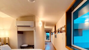 Quarto de hotel com uma cama, janela com vista, corredor e porta que dá para outro quarto.