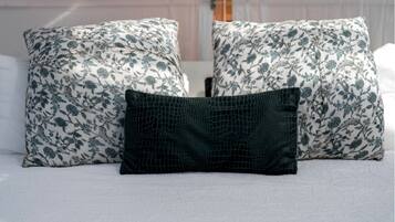 A bed with two floral-patterned pillows and a single textured pillow.