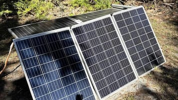 Tres paneles solares sobre el suelo, con un fondo natural.