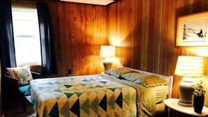 A room with a bed, two bedside lamps, a small table with a plant, and a framed picture on the wall. - Charming Lakeside Cabin Rental near Camp Nine Pines, Wisconsin (Ashland)