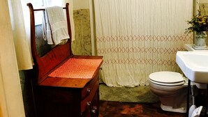 A bathroom with a wooden bench, a toilet, a sink, and a shower curtain. - Charming Lakeside Cabin Rental near Camp Nine Pines, Wisconsin (Ashland)