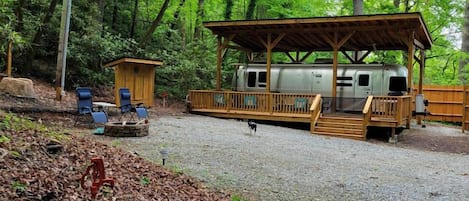A covered outdoor area with a wooden deck, a small wooden structure, and a gravel path.