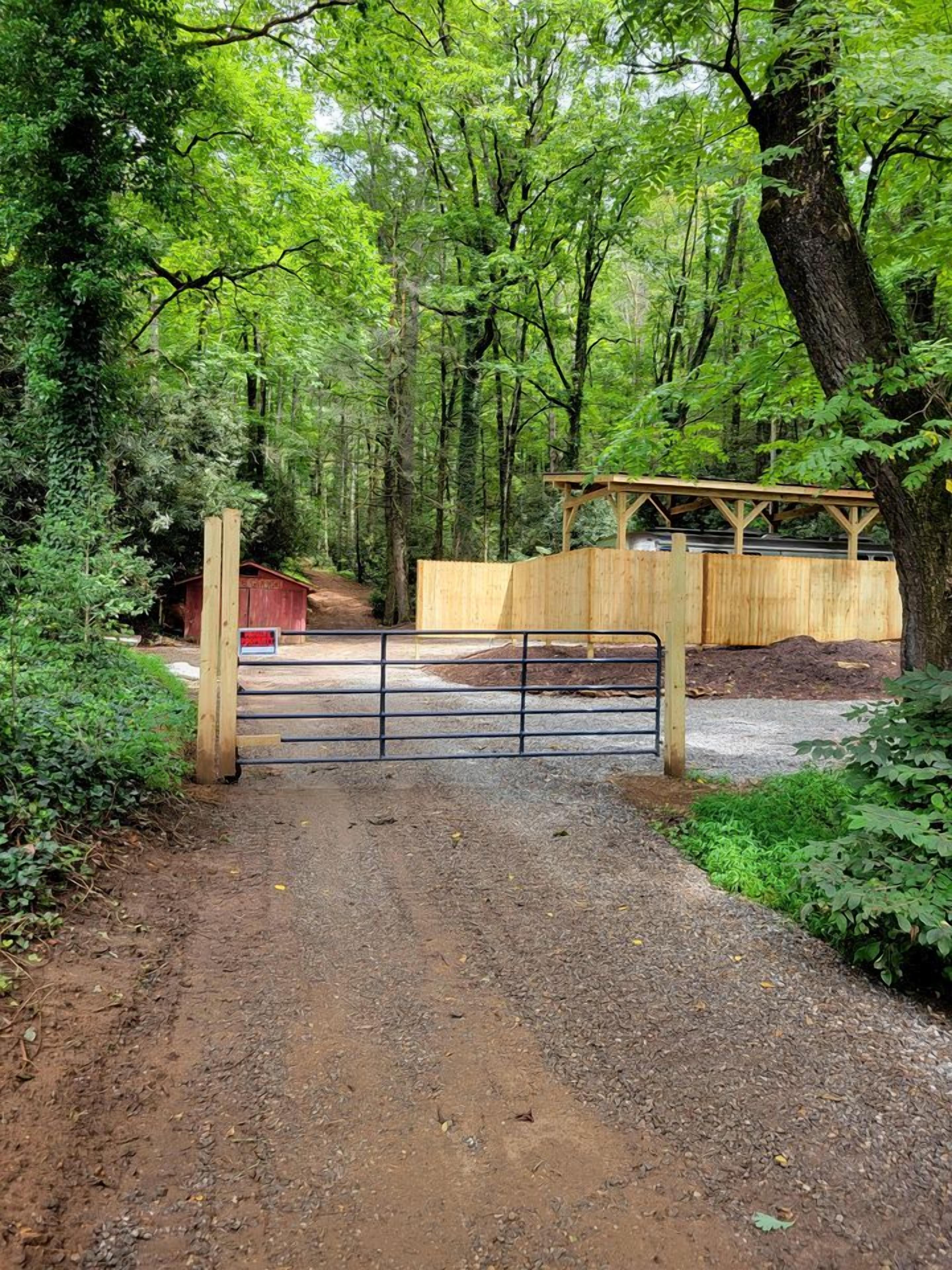 Un sendero de grava que conduce a un portón de madera en un área boscosa.