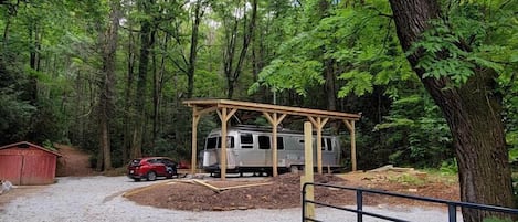 Un camping con zona de estacionamiento techada para vehículos recreativos, caminos de grava y entrada cercada.