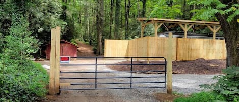 Un sendero de grava que conduce a un portón de madera en un área boscosa.