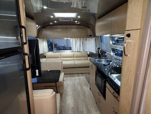 Ein kompaktes Wohnmobil-Interieur mit einer Küchenzeile, einer Sitzecke und einem Esstisch.