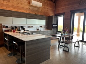 A modern kitchen with a large island, bar stools, and a dining area with benches. - Beautifully Renovated Barn Ideal for Glamping at Flathead Lake, Montana (Somers)