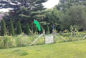 A garden with a wooden fence, a white picket fence, and various plants.