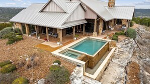 Une grande maison dotée d’une piscine, d’une façade en pierre et offrant une vue sur le paysage environnant.