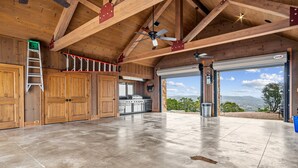 Un garage spacieux doté d’un sol en béton, de poutres en bois et d’une grande porte de garage.