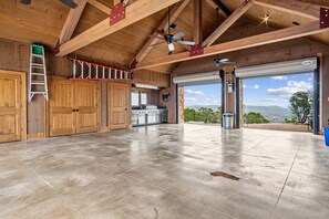 Eine geräumige Garage mit Betonboden, Holzbalken und einer großen Garagentür.